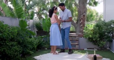 Çeşitli çiftler bahçede piknik battaniyesinde şampanya ve meyvelerle yıldönümlerini kutluyor. Kutlama, romantizm, piknik, bahçe, mutluluk, birliktelik, doğa, çift