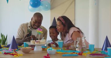 Çeşitli aileler doğum günlerini keklerle kutluyor, parti şapkaları takıyor ve evde birlikte gülümsüyorlar. Kutlama, mutluluk, birliktelik, neşe, şenlik, vesile