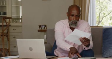 Evrakları inceleyen kıdemli bir adam, ev telefonuyla konuşurken, kopyalama alanı. İş, telekomünikasyon, danışmanlık, belgeleme, iletişim, çoklu görev