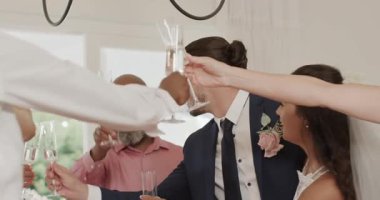 Düğün kadehlerini kaldırmak için baş masada flüt kaldırırken gelin ve damat kadeh tokuşturuyor. Kutlama, zarafet, romantizm, neşe, lüks, arkadaşlık, etkinlik