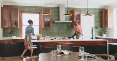 Çeşitli çiftler modern mutfakta birlikte yemek hazırlıyorlar, evde özenle sofrayı hazırlıyorlar. Yemek pişirme, takım çalışması, ev hayatı, yaşam tarzı, aşçılık, birliktelik