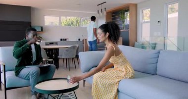 Modern evdeki çeşitli arkadaşlar, sehpa ve not panosuyla koltukta heyecanlı bir şekilde sohbet ediyorlar. Kutlama, sohbet, modern, bağlılık, arkadaşlık, yaşam tarzı, dekor, evde