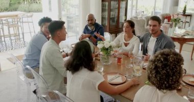 Çeşitli arkadaşlar sohbet ediyor sonra da yemek odasındaki ahşap masanın üstünde şarap kadehlerini kaldırıyorlar. Sosyalleşme, kutlama, yemek, neşe, dostluk, misafirperverlik, iç mekan.