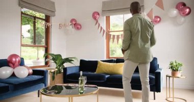 Evdeki kutlama için balonlar ve afişlerle oturma odasını dekore eden bir adam. Parti, dekorasyon, şenlik, hazırlık, vesile