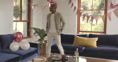 Adam doğum günü kutlaması için balonlarla ve afişlerle oturma odasını dekore ediyor. Parti, festival, iç mekan, dekorasyon, etkinlik, hazırlık