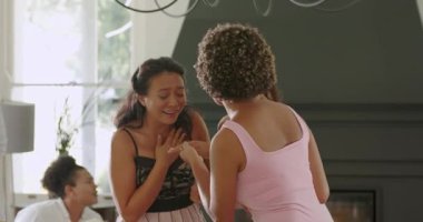 Orta yaşlı bir adam el kol hareketi yapıyor, çeşitli bayan arkadaşları selamlıyor, şöminenin yanında yüzük kutusu sunuyor. Kutlama, dostluk, neşe, sürpriz, zarafet, yakınlık, kilometre taşı