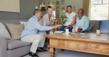 Gülümseyen farklı yaşlılar evde birlikte vakit geçiriyorlar. Hediye alışverişi yapıyorlar ve gülüyorlar. dostluk, bağ, kutlama, mutluluk, birliktelik, emeklilik