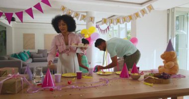 Çeşitli aile, evde renkli balonlar ve süslemelerle dolu doğum günü partisi masası hazırlıyor. Kutlama, farklı aile zamanları, birliktelik, mutluluk, neşeli, neşeli