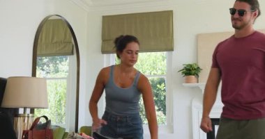 Oturma odasındaki bavullara gradyan bluz ve çiçekli gömlek doldurup seyahate hazırlanan çift. Seyahat, paketleme, yaşam tarzı, organizasyon, aksesuarlar, gündelik, yerli