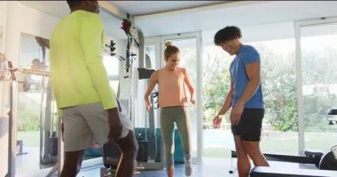 Genç çift spor salonunda antrenörle egzersiz yapıyor, birlikte spor yapmayı seviyorlar. Spor, egzersiz, eğitim, kişisel antrenör, sağlıklı yaşam tarzı.