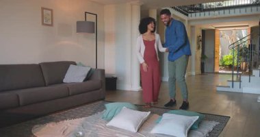 Elinde çiçekler olan bir kadın. Oturma odasında bir erkekle gülüyor ve yürüyor. Mutlu, aşk, farklı çiftler, ilişki, birlikte, ev