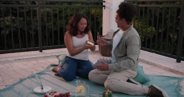 Kurdeleli hediye kutusunu değiştiren çift terasta selfie çekerken sürpriz eşyalar keşfediyor. Romantizm, kutlama, şefkat, açık hava, samimiyet, rahatlık, canlılık