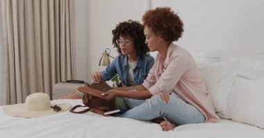 Evde broşür ve bavullarla seyahat etmeyi planlayan lezbiyen çift aynı cinsiyetten. lgbt, tatil, ilişki, mutluluk, ev hayatı, macera