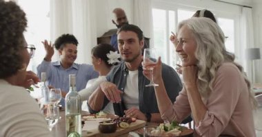 Çeşitli arkadaşlar ve aileler, yeni geleni kucaklayarak karşılayan şarap kadehleriyle evde yemek yiyorlar. Sosyal toplanma, kutlama, bağlantı, sıcaklık, dostluk, samimiyet, köylülük