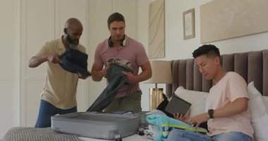 Odada çeşitli aileler tablet telefonları inceliyor. Sarılmak için kıyafet paketliyorlar. Aile, toplanma, seyahat, birleşme, yaşam tarzı, kaynaşma, organize