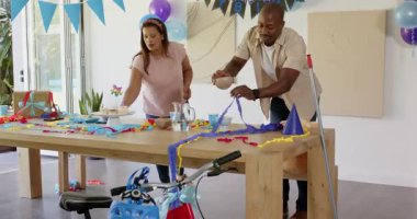 Doğum günü partisi masasını dekore etmek, renkli flamalar ve balonlar düzenleyen bir kadın, evde. Kutlama, parti dekorasyonu, şenlik, dekorasyon, etkinlik planlaması