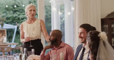 Kıdemli beyaz kadın Afrikalı Amerikalı adamın kolunu tutuyor, resepsiyonda düğün kadehi için flüt kaldırıyor. Kutlama, dostluk, zarafet, şenlik, şenlik, sade, sıcak.