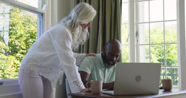 Üst düzey çift, ofiste kutlama yaparken dizüstü bilgisayara bakıp notlar yazıp kâğıt atıyorlar. İşbirliği, takım çalışması, üretkenlik, modern, canlı, pozitif, dinamik