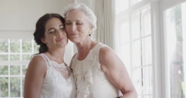 Gelin, nedime küpelerini süite yerleştirirken annesinin koluna bilezik takmayı teklif ediyor. Sevgi, aile, zarafet, kutlama, kadınlık, hazırlık, bağlar