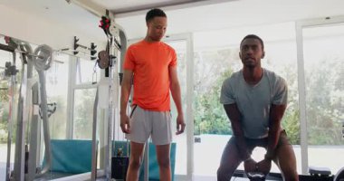 Ağırlıklarla egzersiz yapan Afrika kökenli Amerikalı erkekler spor salonunda güç antrenmanına odaklanıyor. Fitness, egzersiz, dambıl, vücut geliştirme, erkek, evde