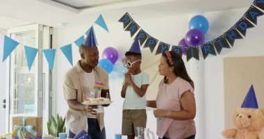 Çeşitli aileler evde doğum günü kutluyor, parti şapkaları takıyor ve pastanın tadını çıkarıyorlar. Kutlama, doğum günü partisi, mutluluk, şenlik, birliktelik