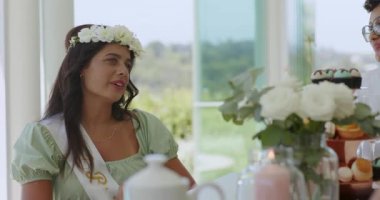 Verandadaki çeşitli bayan arkadaşlar yorum yapıyor, müstakbel gelin adayları el kol hareketi yapıyor, çay takımından telefonları seçiyor. Kutlama, dostluk, zarafet, açık hava, yaşam tarzı, neşeli, sosyalleşme