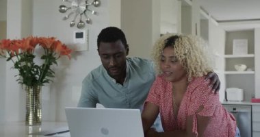 Mutfakta dizüstü bilgisayara gülümseyen ve evde online içeriğin keyfini çıkaran bir çift. Teknoloji, yaşam tarzı, ilişki, mutluluk, internet, dijital