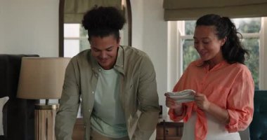 Çeşitli çiftler yatak odasında bebek kıyafetlerini sınıflandırıyor, bebek tekmelerini diz çökerek kutluyorlar. Aile, beklenti, yakınlık, şefkat, ev, sıcaklık, bağlantı