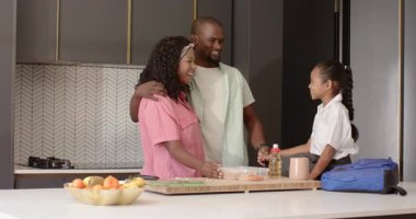 Çeşitli aileler mutfakta birlikte yemek hazırlıyor, gülümsüyor ve evde kaliteli vakit geçiriyorlar. Yemek pişirme, yemek hazırlama, birliktelik, kaynaşma, aşçılık, yaşam tarzı