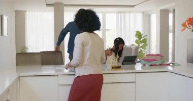 Modern mutfakta sırt çantasıyla kızını kucaklayan, sevgi dolu bir anı paylaşan farklı bir anne. Çeşitli aile, sevgi, sevgi, sabah, ebeveynlik