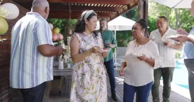 Çeşitli kadınlar bahçe kutlamalarında eğleniyor, ahşap güvertede gülüp sohbet ediyorlar. Toplanma, arkadaşlık, bahçede, parti, mutluluk, sohbet