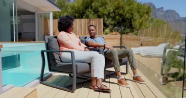 Genç çift terasta dinleniyor, manzaranın tadını çıkarıyor ve manzarayı işaret ediyor. Rahatlama, rahatlama, yaşam tarzı, açık hava, kaynaşma, manzara