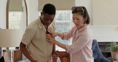 Seyahat kıyafetleri için akıllı telefonları kaydıran ve evde giysileri olan bavulları toplayan farklı çiftler. Macera, seyahat, organizasyon, keşif, yaşam tarzı, minimalizm, arkadaşlık