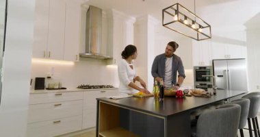 Mutfak adasında soğan doğrayıp salata karıştırırken biber toplayarak kıvılcım saçan çift. Aşçılık, aşçılık, modern, yaşam tarzı, takım çalışması, tazelik, canlı