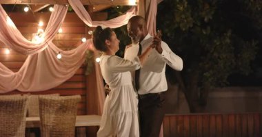 Düğünde, çeşitli çiftler bahçe kutlamalarında tel ışıklarının altında neşeyle dans ediyorlar. Parti, mutluluk, romantizm, gece, festival, bahçede