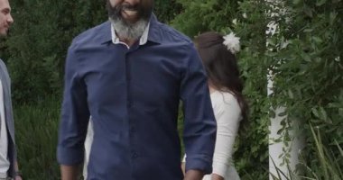 Çeşitli çiftler ve memurlar belgeleri ve yüzük kutusunu değiş tokuş ediyor, tableti çitle imzalamak için tıkırdatıyor. Düğün, tören, kutlama, zarafet, çiçek, açık hava, mutluluk.