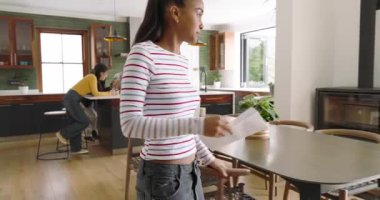 Çizgili gömlekli kadın zarfı açıyor. Mutfak adasında mektup okuyor. Kutlama yapıyor. Arkadaşlar, kutlama, modern, iç mekan, sosyal, heyecan, gündelik