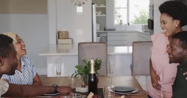 Yemek masasına su döken, farklı arkadaşlarla evde yemek yiyen bir adam. Yemek, toplantı, kutlama, yaşam tarzı, çok kültürlü.