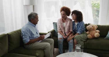 Evde, oturma odasındaki kanepede aynı cinsiyetten gülümseyen lezbiyen çiftle tablet paylaşan yaşlı bir adam. Teknoloji, ev, son sınıf, LGBT, yaşam tarzı, bağlanma