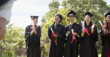 Mezun olurken çeşitli sınıf arkadaşları el çırpıyor, kollarını birleştiriyor ve güneşli çimlere şapka fırlatıyorlar. Kutlama, başarı, birlik, çeşitlilik, başarı, açık hava, gençlik