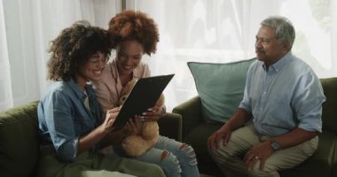 Çift cinsiyetli lezbiyen çift kanepeye oturup oyuncak ayıyı kucaklar, terapistle konuşur, evde. LGBTQ, terapi, danışmanlık, destek, akıl sağlığı, ilişki