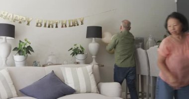 Doğum günü kutlaması hazırlığı, balonlarla ve dekorasyonlarla evi dekore eden yaşlı çift. Festival, yıldönümü, neşeli, emeklilik, kapalı alan, mutluluk