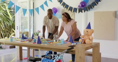 Doğum günü partisi için dekorasyon, evde balonlarla ve parti şapkalarıyla masayı düzenleyen adam. Kutlama, etkinlik, şenlik, dekorasyon, hazırlık, toplanma