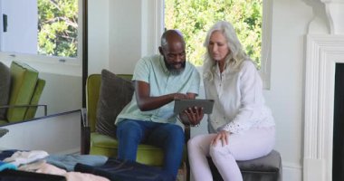 Tableti evde kadın olarak inceleyen çeşitli çiftler anahtarlarla içeri giriyor, tıkırdıyor, kıyafetleri sınıflandırıyor. Dijital okur yazarlık, nesiller arası, modern yaşam tarzı, ev sahnesi, rahat ortam, teknoloji eğitimi, rahat ruh hali.