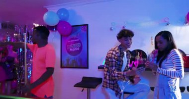 Çeşitli arkadaşlar selfie çektikten sonra bodrumdaki disko partisinde neon ışıkları altında bilardo oynuyorlar. Kutlama, gece hayatı, eğlence, yoldaşlık, canlı, retro, sosyalleşme.