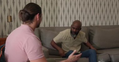 Çeşitli erkek arkadaşlar birbirlerine bakıyorlar ve sarılmadan önce gri koltukta samimi bir şekilde konuşmaya başlıyorlar. Arkadaşlık, duygu, bağlantı, gayri resmi, samimi, sohbet, çağdaş