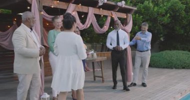 Düğünde, arka bahçedeki seremonide evlilik yemini eden kıdemli çift, arkadaşlarının etrafını sardı. Düğün, kutlama, olgunluk, çeşitli kıdemli arkadaşlar çemberi, bahçede, aşk