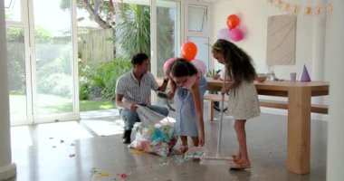 Parti masasının yanında duran, pembe çantalı ve konfeti toplayan genç çift. Kutlama, şenlik, dekorasyon, eğlence, toplanma, neşe, parti