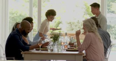 Sunucu tepsisi getirince tetiklenen farklı arkadaşlar ahşap masada yemek tabaklarını paylaşıyorlar. Uyum, sosyallik, kutlama, zarafet, ortam, boş zaman, bağlantı