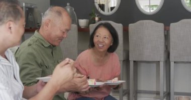 Asyalı yaşlılar pastadan zevk alıyor ve birlikte gülüyorlar, neşeyle kutluyorlar. Son sınıflar, birliktelik, kutlama, yaşlılık, mutluluk, toplanma